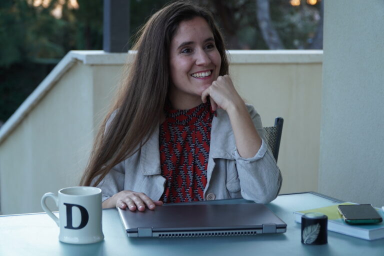 Diana sonriendo sentada con el ordenador en el jardín